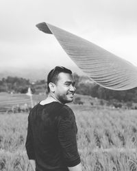 Portrait of smiling man standing on field against sky