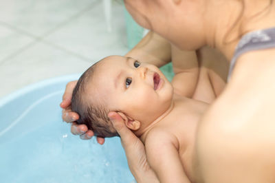 Mother bathing daughter in bathroom