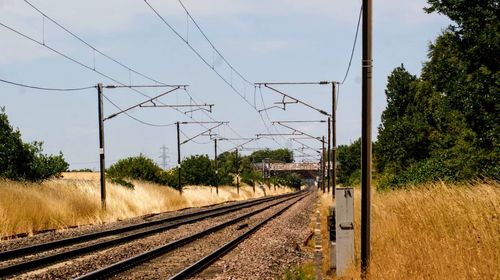 Railroad tracks by electricity pylon against sky