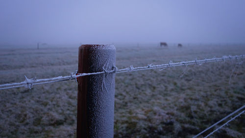 Close-up of wooden fence by sea against sky