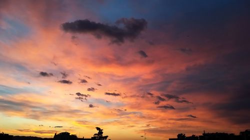 Low angle view of silhouette trees against dramatic sky