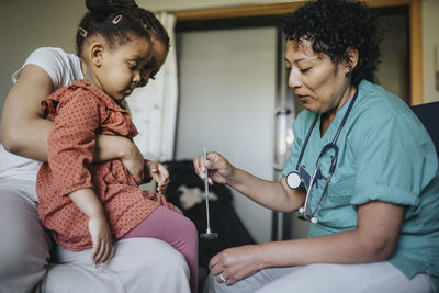 Female doctor with reflex hammer examining girl in clinic