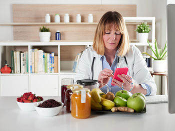 Portrait of smiling young woman using mobile phone while sitting at home