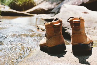 Shoes on rock by stream during sunny day