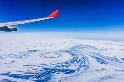 Aerial view of airplane wing over snow covered landscape