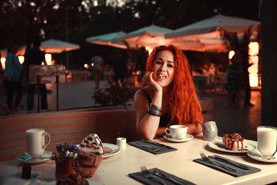 Young woman using phone while sitting on table