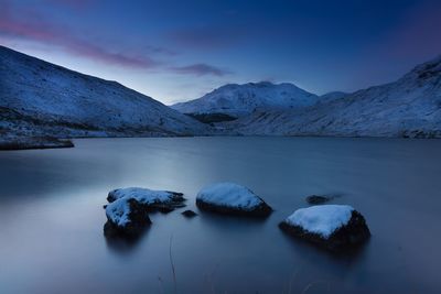 Scenic view of lake and snowcapped mountains against blue sky