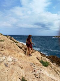 Full length of man on rock at beach against sky