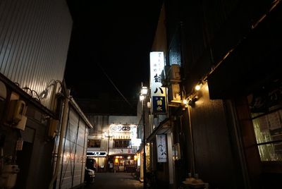 Illuminated street amidst buildings in city at night
