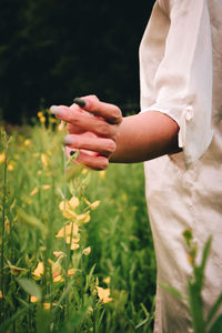 Midsection of woman holding flowers on field