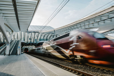 Blurred motion of train at railroad station platform against sky