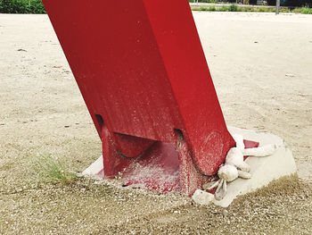 Low section of person with red umbrella on sand