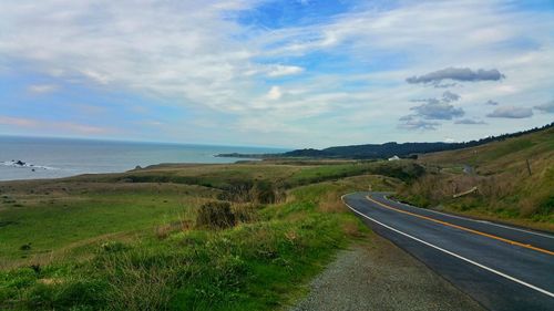 Scenic view of road by sea against sky