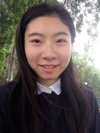 Portrait of smiling young woman standing against trees
