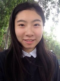 Portrait of smiling young woman standing against trees