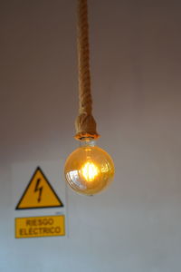 Close-up of illuminated light bulb against wall