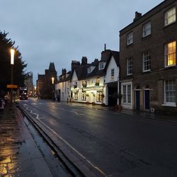 Street amidst buildings against sky at dusk