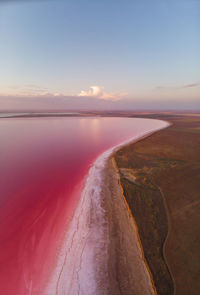 Panorama aerial view of pink salt lake in sunset light with clouds on horizon