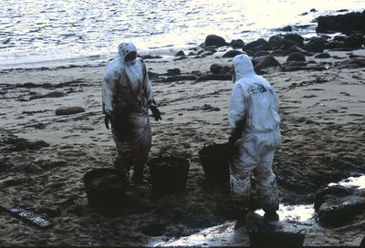 People working on beach against sky