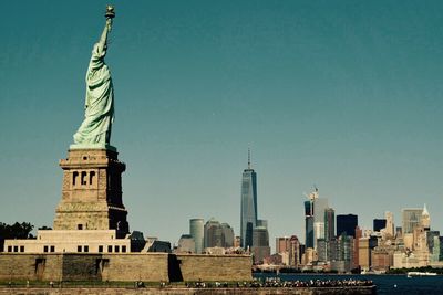 Statue of liberty and cityscape against clear sky