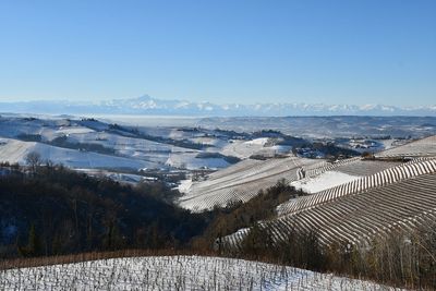 Snow-covered hilly landscape of the langhe area of piedmont with the alps mountain range , alba