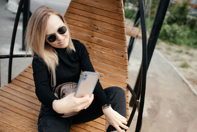 Close-up beautiful 30-year-old woman with glasses is texting and taking 