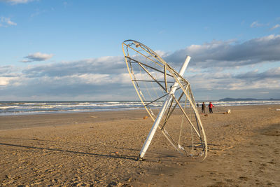 Ferris wheel on beach against sky