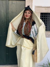 Portrait of young woman standing against wall