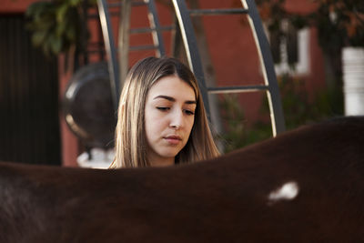 Young blonde woman with her brown horse enjoys a day on the farm.