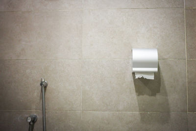 Bathroom tissue and faucet on anthracite tiled wall.