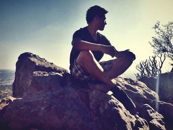 Young man with arms raised against sky