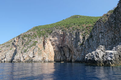 Scenic view of sea and mountains against clear blue sky