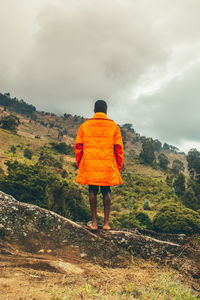 Rear view of a young adult standing against mountain