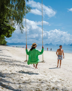 Rear view of boy playing at beach against sky