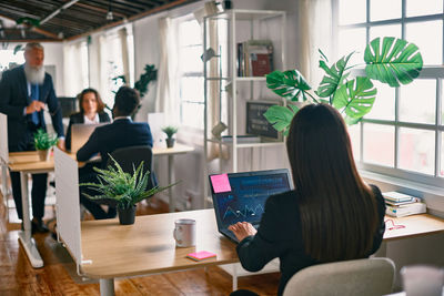 Rear view of woman using laptop at office