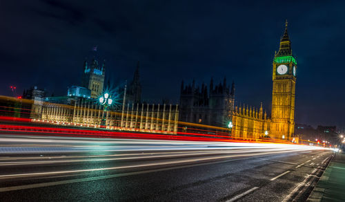 Light trails on street by big ben at night