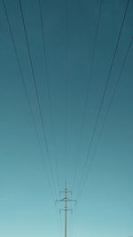 Low angle view of electricity pylon against blue sky