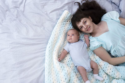 Young beautiful mother with her newborn baby boy lying in bed at home. selective focus. copy space.