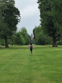 Man cycling on golf course against sky