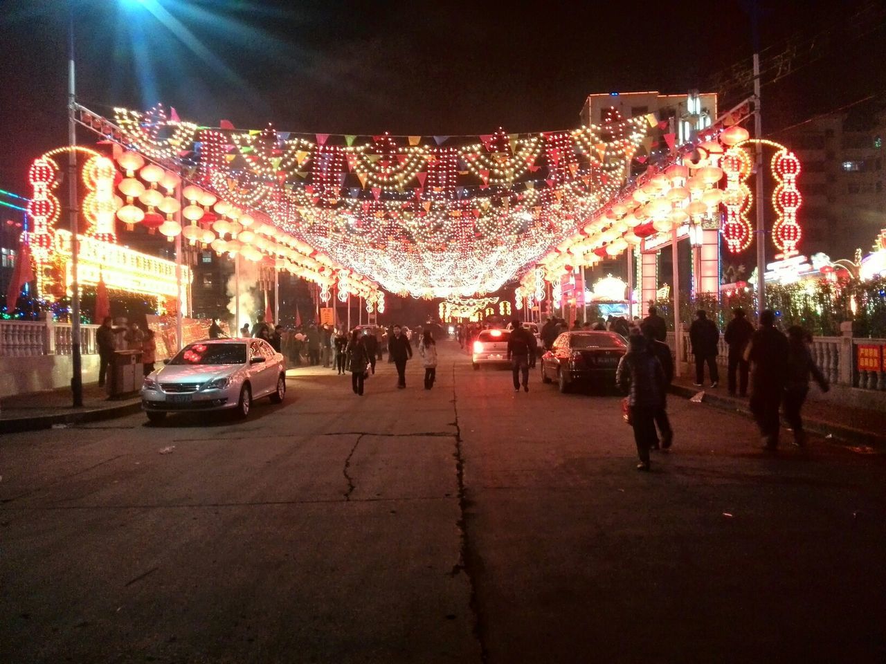 large group of people, illuminated, street, night, person, men, lifestyles, building exterior, city life, city, leisure activity, mixed age range, city street, road, celebration, built structure, walking, architecture, transportation