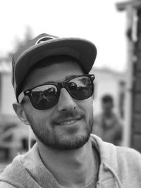 Close-up portrait of man wearing sunglasses and cap outdoors