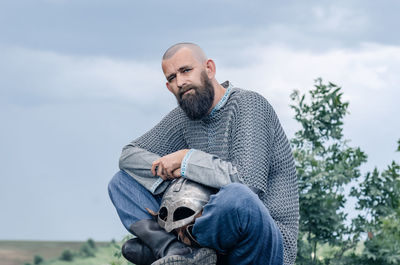 Side view of man in medieval viking clothing. metal helmet and chain mail. blurred background.
