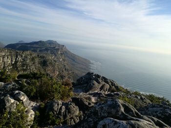 Scenic view of rocks by sea against sky