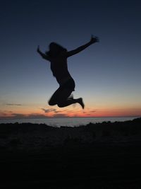 Silhouette of man jumping at sunset