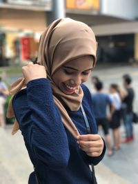 Smiling woman wearing hijab standing in city