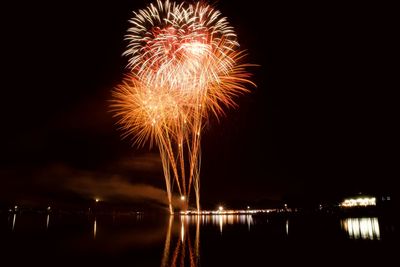 Firework display over lake at night