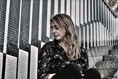 Young woman sitting on steps in city