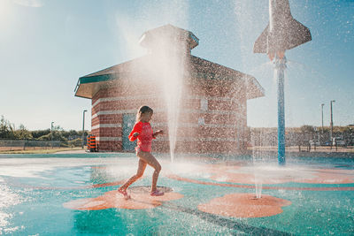 Cute adorable caucasian funny girl playing on splash pad playground on summer day. happy child 