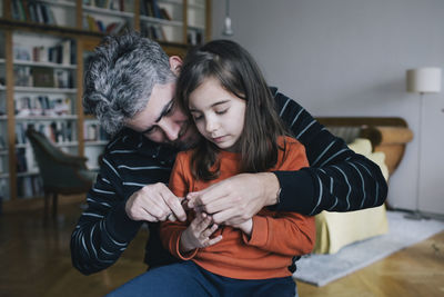 Father cutting nails of girl with scissor at home
