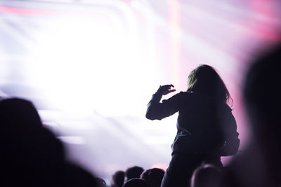 Silhouette of woman photographing at music concert